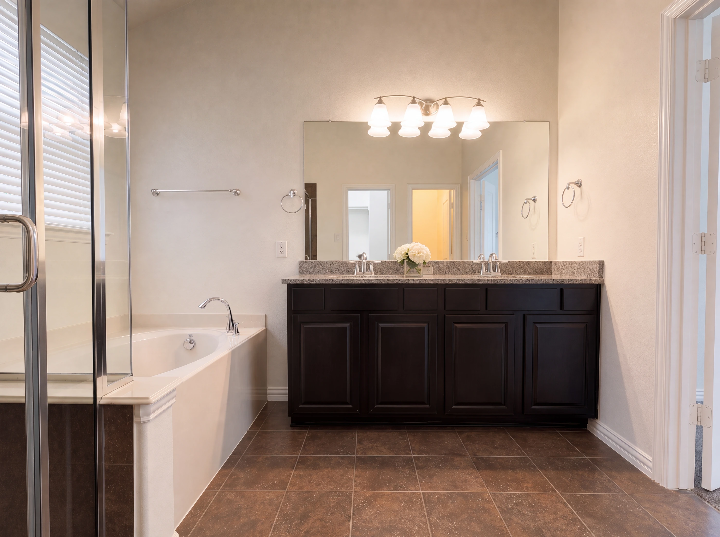 Corner garden tub, separate glass shower and dual-sink granite vanity